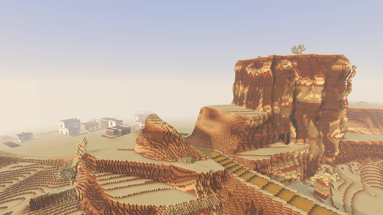 A layered red mesa stands above the desert sand at dawn.